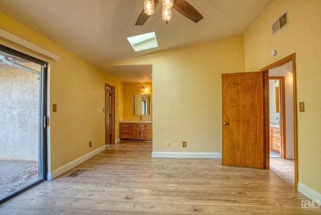 spare room with vaulted ceiling with skylight, ceiling fan, and light hardwood / wood-style floors