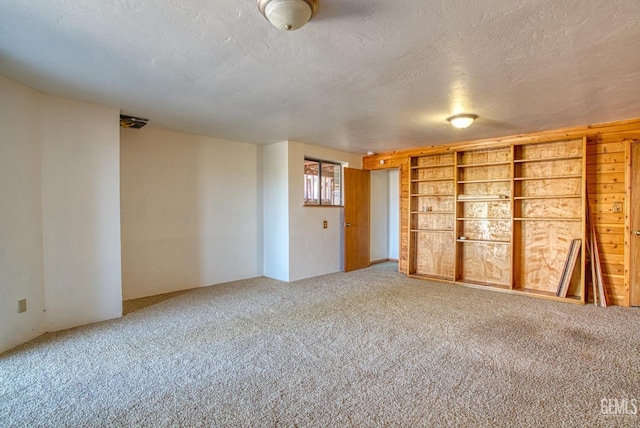 carpeted spare room with built in shelves and a textured ceiling