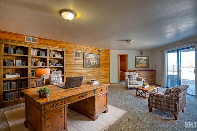 carpeted office space with wood walls and a textured ceiling