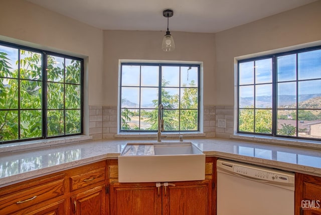 kitchen featuring pendant lighting, sink, white dishwasher, and a healthy amount of sunlight