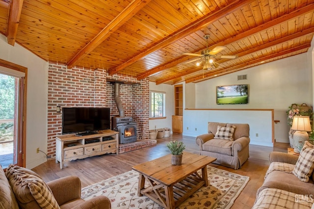 living room featuring wooden ceiling, a wood stove, lofted ceiling with beams, light hardwood / wood-style flooring, and ceiling fan