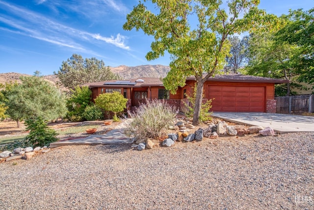 single story home featuring solar panels, a garage, and a mountain view