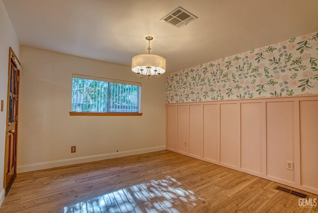 empty room with light hardwood / wood-style flooring and an inviting chandelier