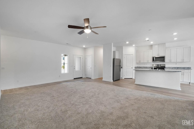 unfurnished living room featuring light carpet and ceiling fan