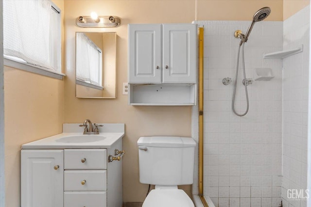 full bath with tiled shower, vanity, and toilet