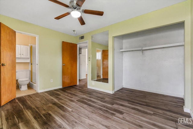 unfurnished bedroom featuring a closet, ensuite bathroom, ceiling fan, wood finished floors, and baseboards