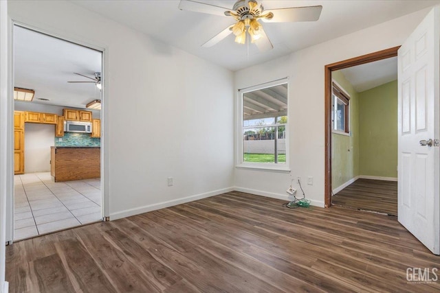 spare room with a ceiling fan, baseboards, and wood finished floors