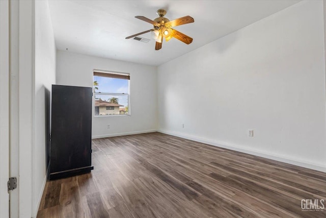 empty room featuring ceiling fan, wood finished floors, visible vents, and baseboards