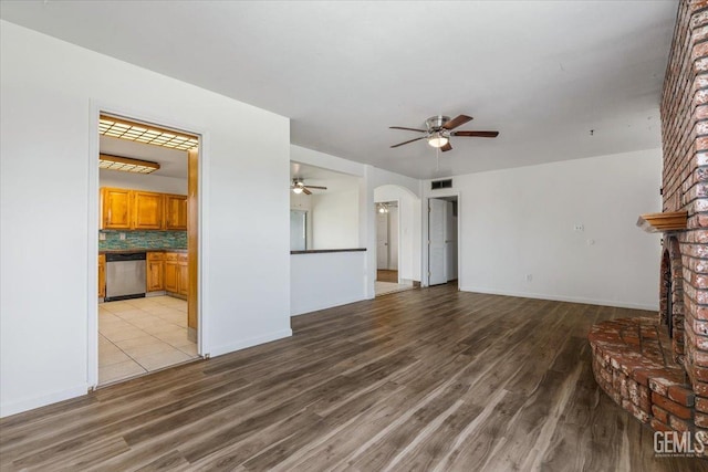 unfurnished living room featuring visible vents, a fireplace, arched walkways, and light wood-style flooring