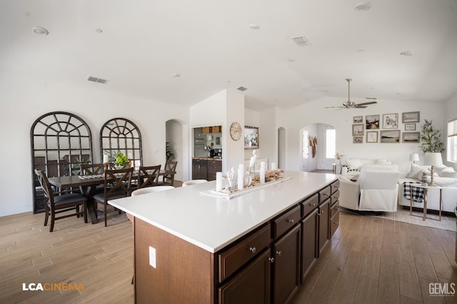3312 Whispering Brook Ln, Shafter, CA 93263 - kitchen with arched walkways, light wood-style floors, ceiling fan, a kitchen island, and plenty of natural light
