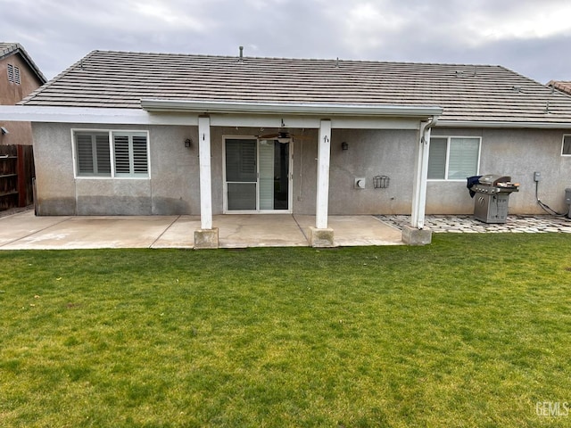 rear view of house featuring ceiling fan, a patio, and a lawn
