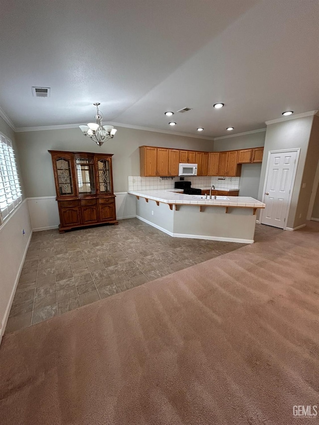 kitchen with carpet floors, decorative light fixtures, tile counters, and kitchen peninsula