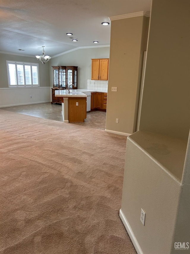 kitchen featuring decorative light fixtures, sink, a chandelier, ornamental molding, and light carpet