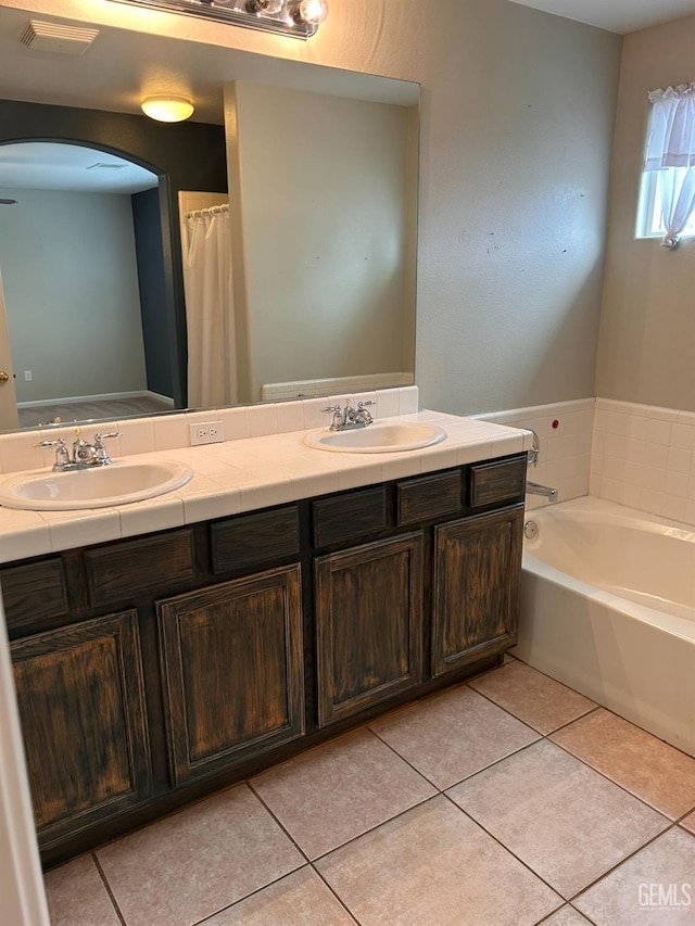 bathroom featuring vanity, tile patterned flooring, and a washtub