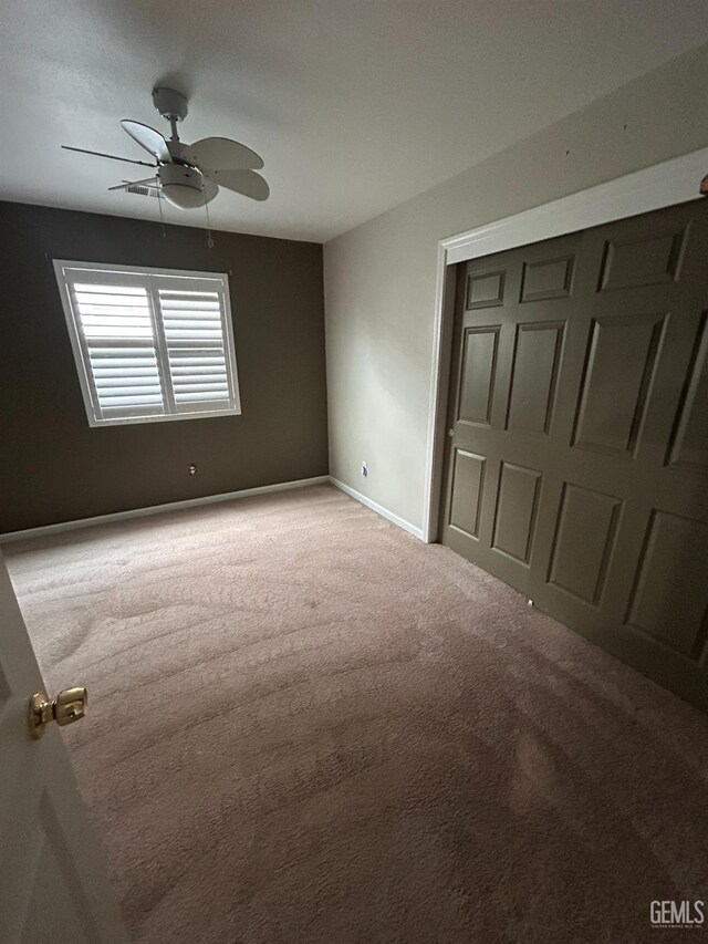 unfurnished bedroom featuring carpet floors, ceiling fan, and a closet