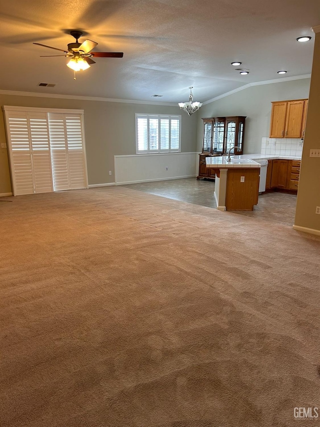 unfurnished living room with crown molding, carpet, sink, and ceiling fan with notable chandelier