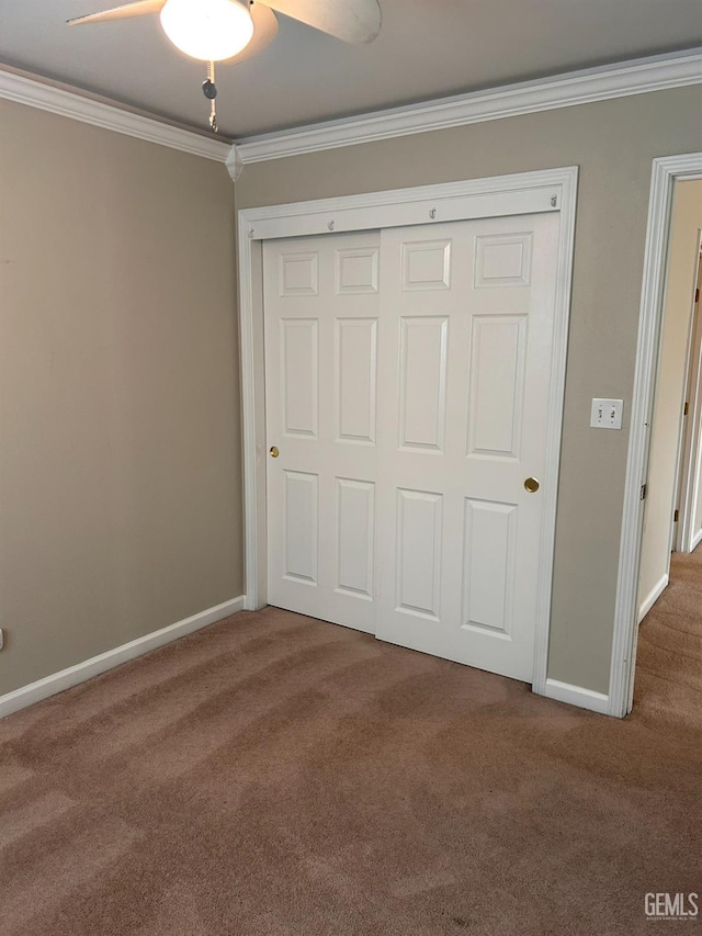 unfurnished bedroom featuring crown molding, a closet, ceiling fan, and carpet