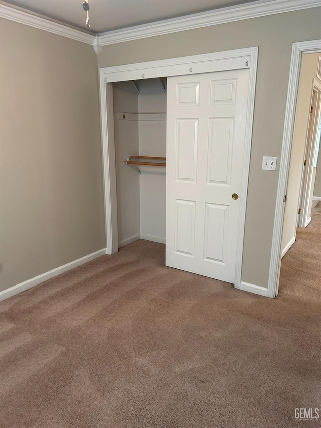 unfurnished bedroom featuring ornamental molding, carpet flooring, and a closet