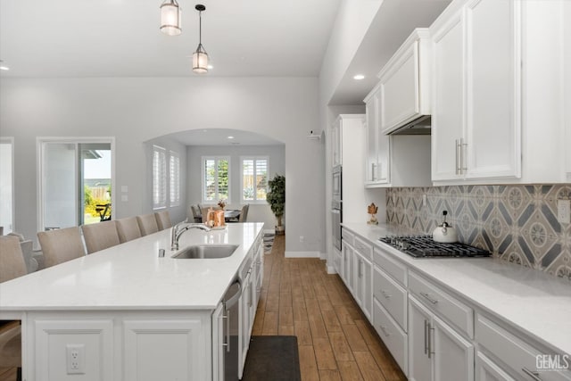 kitchen featuring pendant lighting, stainless steel gas stovetop, a kitchen island with sink, sink, and white cabinetry