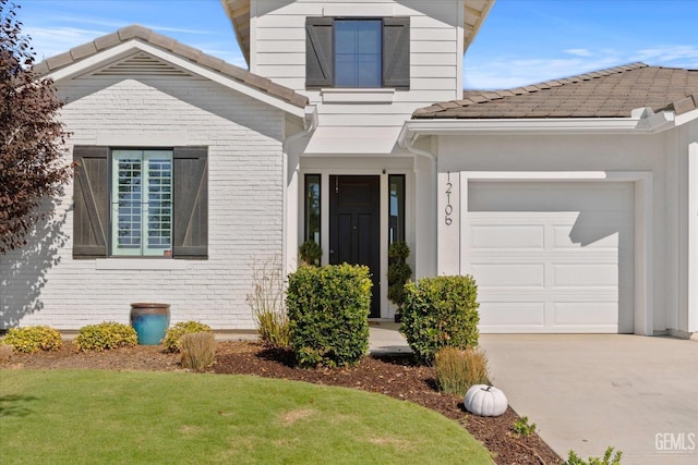 doorway to property featuring a garage and a lawn