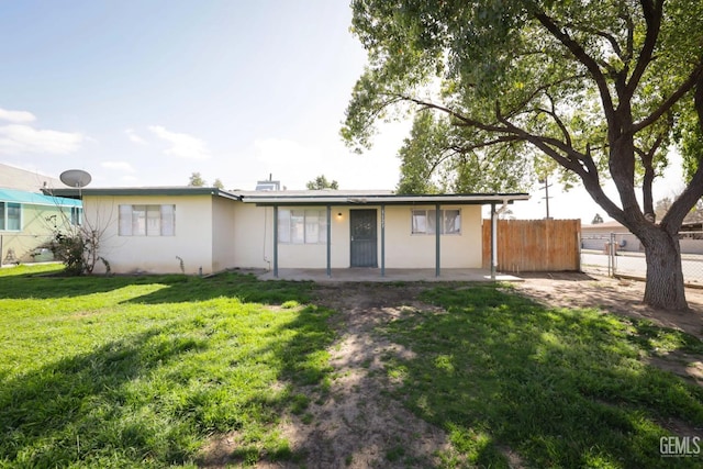 view of front facade with a patio, a front yard, fence, and stucco siding