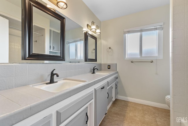 full bath featuring double vanity, baseboards, tile patterned floors, and toilet