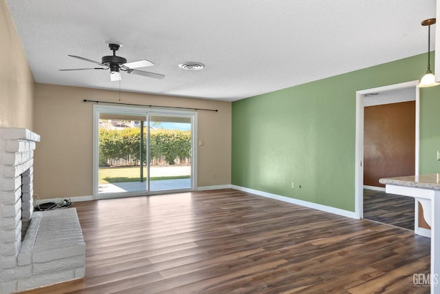 unfurnished living room with ceiling fan, dark wood-type flooring, baseboards, a textured ceiling, and a fireplace