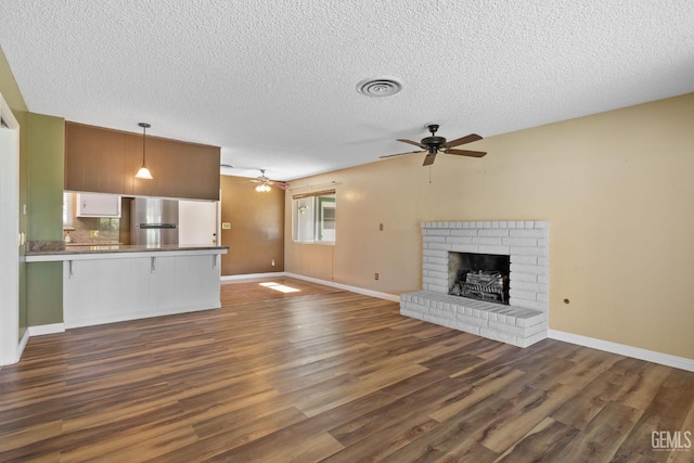unfurnished living room with a ceiling fan, dark wood-type flooring, a textured ceiling, baseboards, and a fireplace