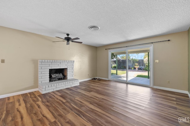 unfurnished living room featuring wood finished floors, ceiling fan, a fireplace, baseboards, and a textured ceiling