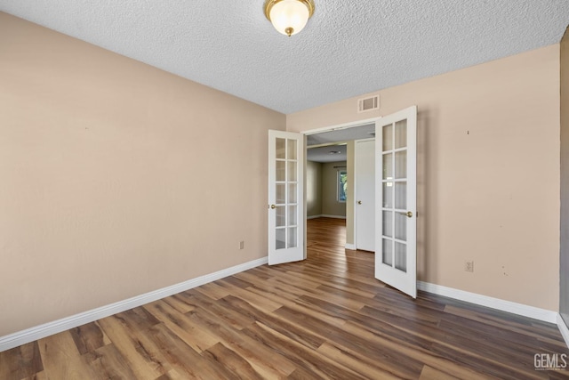 unfurnished room featuring french doors, baseboards, dark wood-style floors, and a textured ceiling