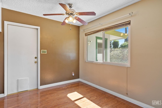 spare room with ceiling fan, wood finished floors, baseboards, and a textured ceiling