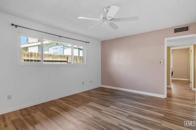 unfurnished room featuring a textured ceiling, wood finished floors, a ceiling fan, and baseboards