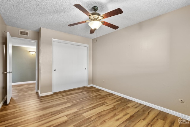 unfurnished bedroom featuring light wood finished floors, a closet, baseboards, and a textured ceiling