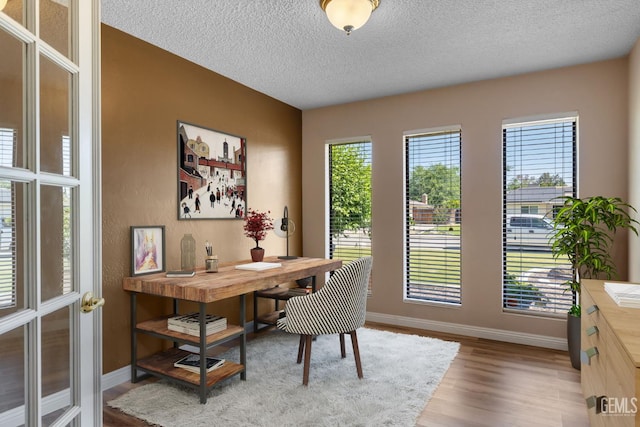 office featuring a textured ceiling, wood finished floors, and baseboards