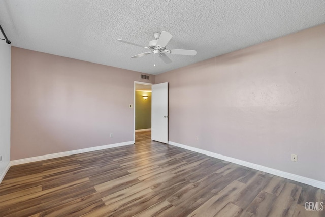 empty room featuring wood finished floors, a ceiling fan, baseboards, and a textured ceiling