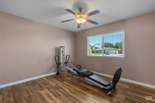 workout room with baseboards, wood finished floors, ceiling fan, and a textured ceiling