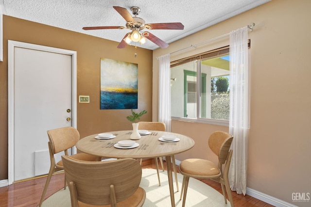 dining room featuring a ceiling fan, baseboards, a textured ceiling, and wood finished floors