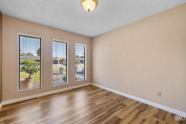 spare room with wood finished floors, baseboards, and a textured ceiling