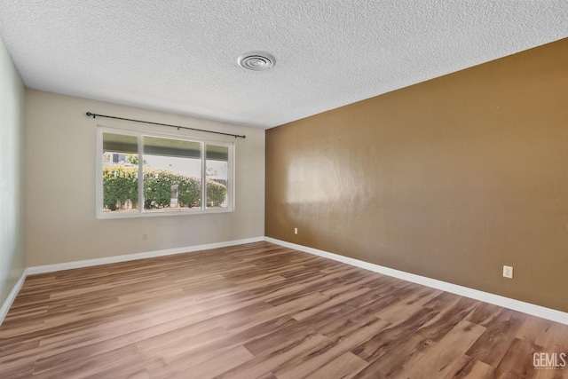 unfurnished room featuring wood finished floors, a textured ceiling, and baseboards