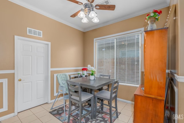 tiled dining area with ceiling fan and ornamental molding