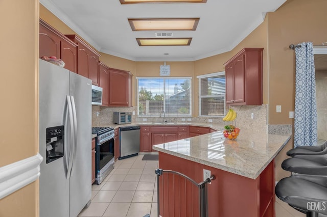 kitchen with light stone countertops, appliances with stainless steel finishes, tasteful backsplash, and light tile patterned flooring