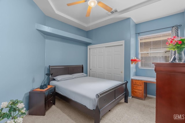 bedroom with a closet, ceiling fan, and light colored carpet