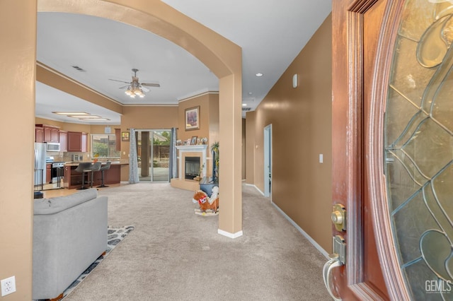 living room with carpet, ceiling fan, and ornamental molding