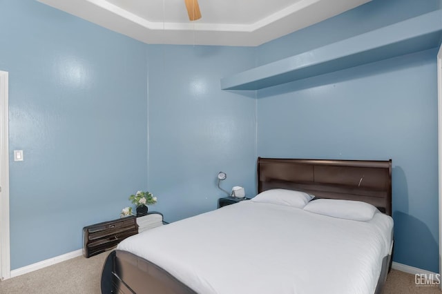 carpeted bedroom featuring a raised ceiling and ceiling fan