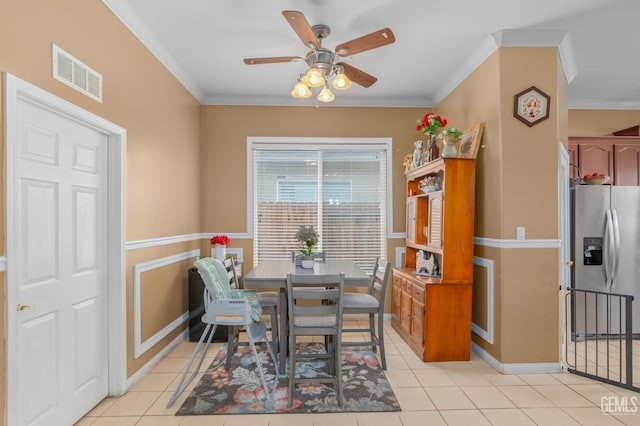 tiled dining space featuring ceiling fan and ornamental molding