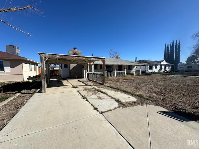 ranch-style home with a carport, concrete driveway, and a chimney