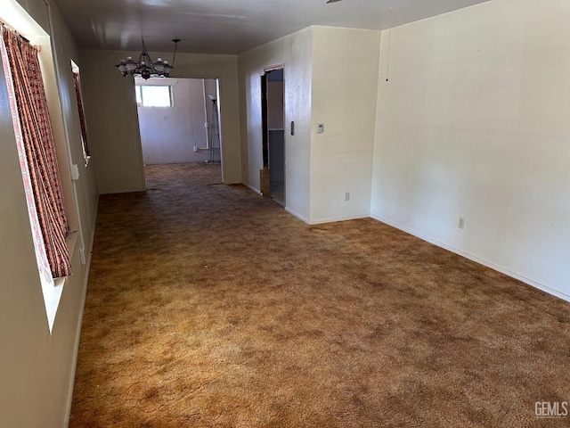 carpeted spare room featuring a chandelier