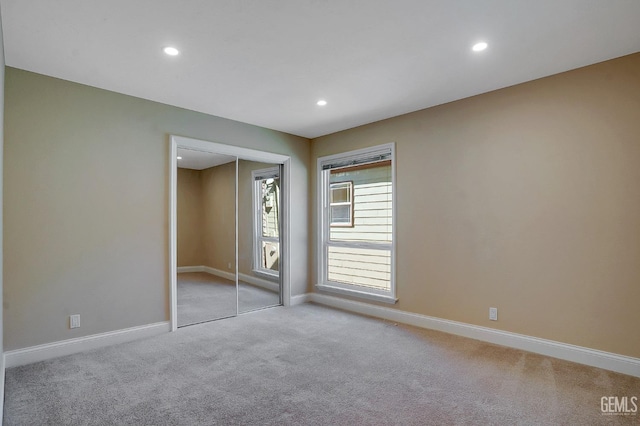 unfurnished bedroom with light colored carpet and a closet