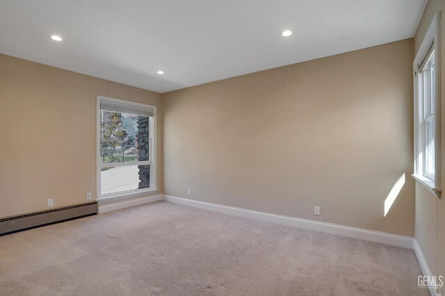 carpeted empty room with baseboard heating and plenty of natural light