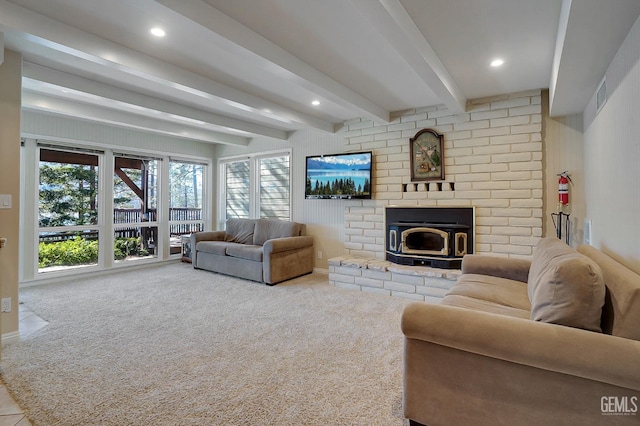 living room with beamed ceiling, carpet, and a wood stove